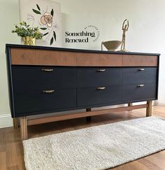 a black and brown dresser sitting on top of a wooden floor next to a rug