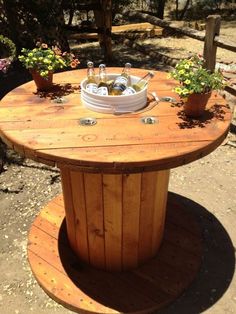 a wooden table with two buckets and bottles on it sitting in the middle of a yard