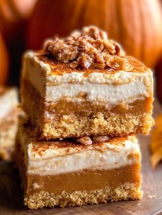 three pieces of cake sitting on top of a wooden cutting board next to pumpkins