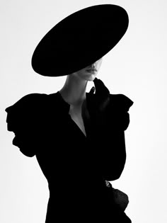 a woman in a black dress and large hat