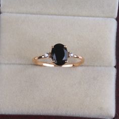 a black diamond ring sitting on top of a velvet case