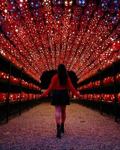 a woman walking down a walkway covered in lights