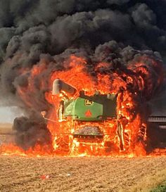 a tractor that is on fire in the middle of a field