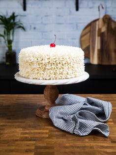 a white cake sitting on top of a wooden table next to a blue and white napkin