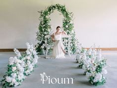 a woman is sitting on a chair surrounded by flowers and greenery in front of her