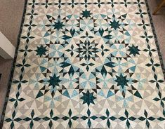 a blue and white quilt is laying on the floor in front of a table top