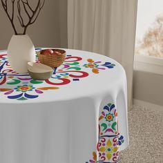 a white table cloth with multicolored designs on it and a bowl of fruit