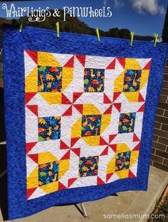 a blue and yellow quilt hanging on a clothes line with the words, whirrlig