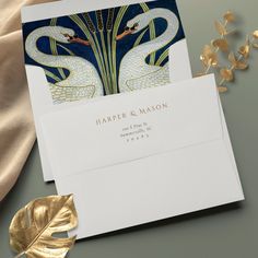 two white swans on a blue background with gold foil leaves and a card that reads, harper & mason