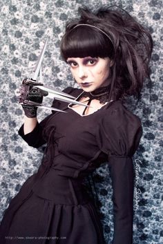 a woman dressed in black holding two scissors