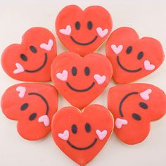 heart shaped cookies decorated with smiley faces are arranged in a pyramid on a white surface