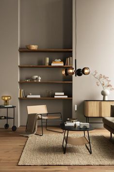 a living room filled with furniture next to a wall mounted book shelf on top of a hard wood floor