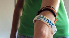 a close up of a person wearing a wristband with the word uwc on it