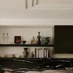 shelves with vases and books on them in a room that has been painted white