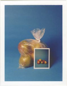 two apples in a plastic bag next to an apple on a blue background with a white frame