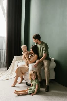 a family sitting on the floor in front of a window with their baby and toddler