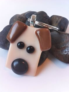 a brown and white dog keychain sitting on top of some rocks