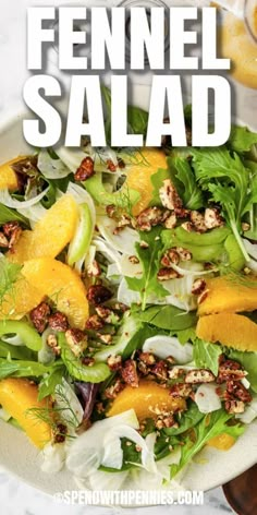 a salad with oranges, lettuce and walnuts on it in a white bowl