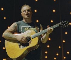 a man holding a guitar while standing on stage