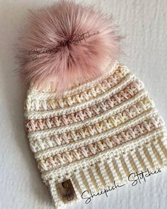 a crocheted hat with a pink pom - pom on top of it