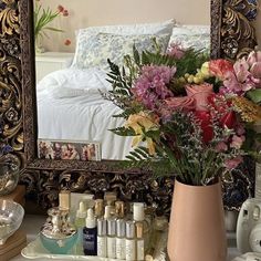 a vase filled with flowers sitting on top of a table next to a mirror and other items