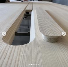 a close up of a wooden table with a metal handle on the edge and a person in the background