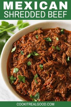 mexican shredded beef in a white bowl with cilantro garnish