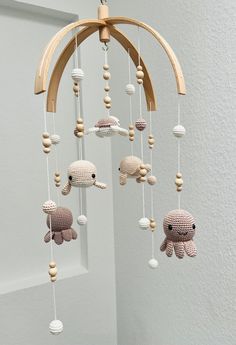 a crocheted octopus mobile hanging from a wooden hanger in a white room