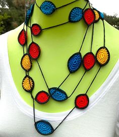 a multicolored crocheted necklace on a mannequin neckpiece with matching beads