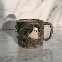 a coffee cup with an image of a ghost in the middle of it on a marble countertop