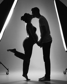 a man and woman kissing in front of a photo studio light with their arms around each other