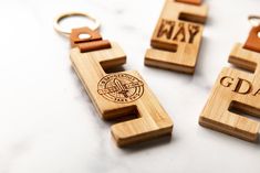 three wooden key chains with the words gay on them