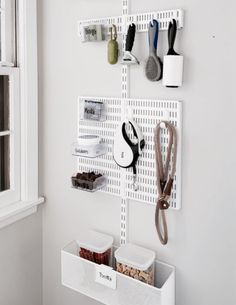 a white wall mounted shelf with scissors and other items