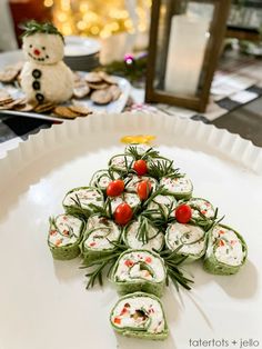 a white plate topped with sushi rolls covered in veggies next to a snowman