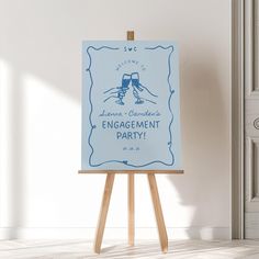 an easel stands in front of a white wall with a blue sign that says engagement party