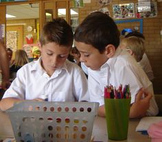 two young boys sitting at a table with pencils in front of them