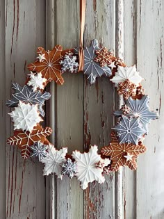 a wreath hanging on the side of a wooden door with snowflakes and leaves