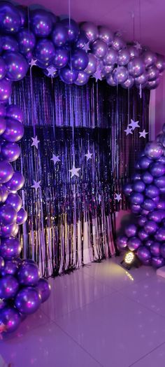 purple and silver balloons are hanging from the ceiling