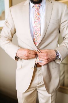 a man wearing a suit and tie with his hands in his pockets as he adjusts his shirt