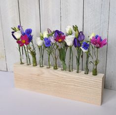 there are many flowers in the vases on this wooden stand, and they look like they were made out of glass bottles