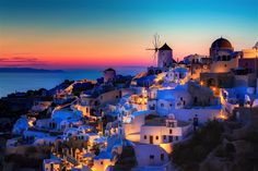 the sun is setting over some white buildings and windmills in oia, greece