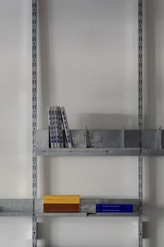 a shelf with books on it in a room that is white and has metal shelving