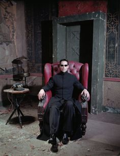 a man sitting in a red chair with his legs crossed