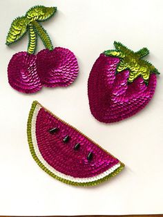 three pieces of sequinated fruit are shown on a white surface, including one piece of watermelon