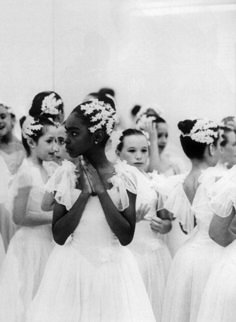 a group of women in white dresses standing next to each other with their hands together