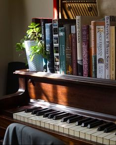 an old piano with books on it and a potted plant