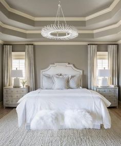 a white bed sitting in a bedroom next to two lamps on either side of the bed