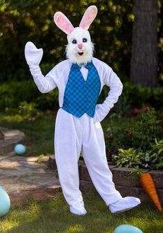 a man dressed as a bunny standing in the grass next to some blue and white eggs