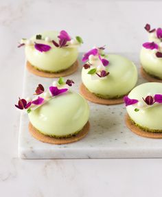 four small desserts with flowers on top of them