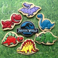 decorated cookies in the shape of dinosaurs on green grass with name and date for each cookie